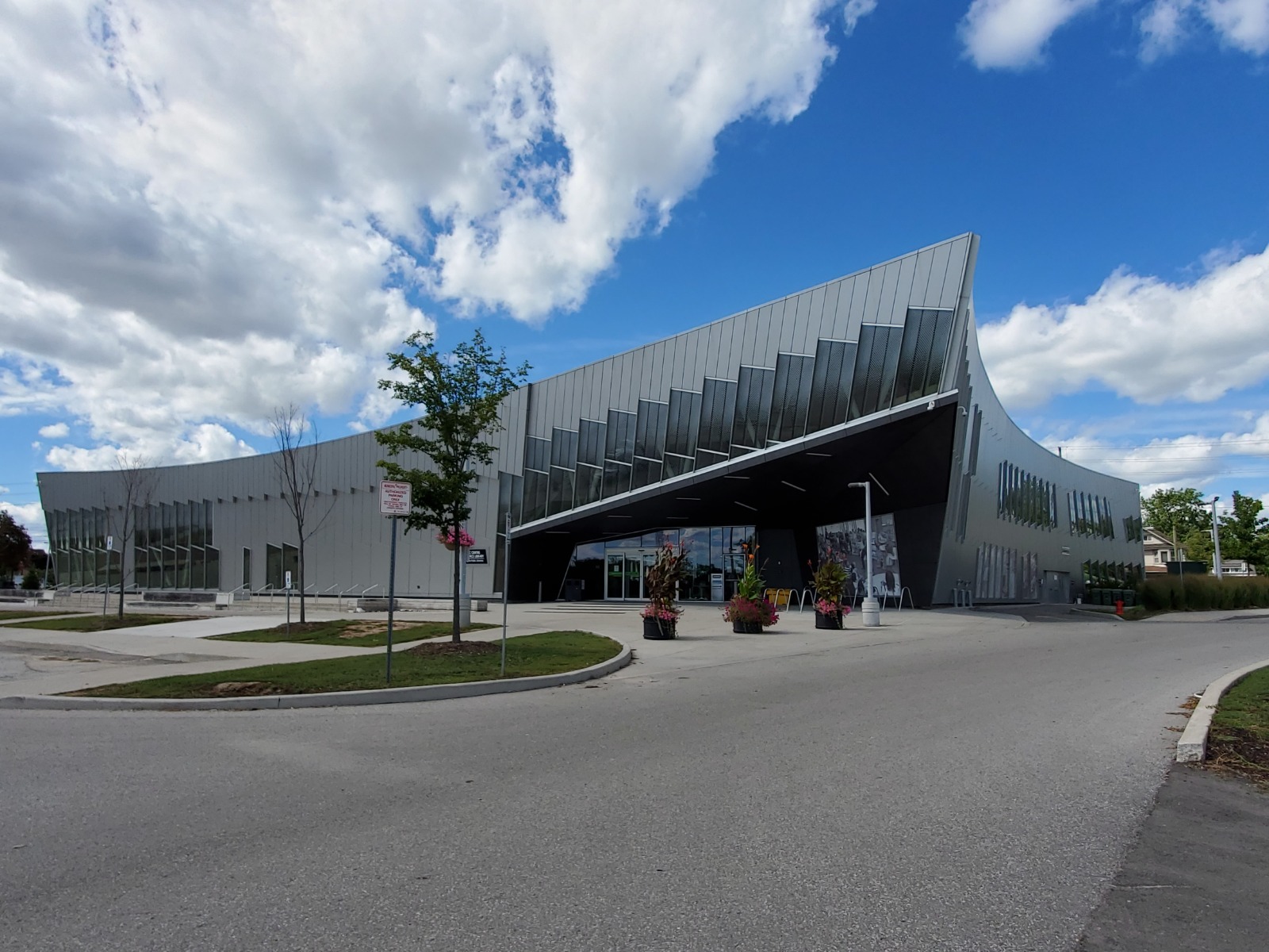 Image of the modernized exterior of the Chancellor Community Centre in Vaughan, featuring a sleek metallic façade, large windows, and landscaped entrance with potted plants, restored by ICON Restoration.
