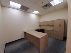 Image of a newly renovated office at the Civic Centre Resource Library in Vaughan, featuring a wooden desk, overhead cabinets, modern lighting, and gray flooring, upgraded by ICON Restoration.
