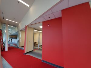 Image of a renovated hallway inside the Civic Centre Resource Library in Vaughan, featuring red flooring, modern lighting, glass walls, and a red accent wall, upgraded by ICON Restoration.