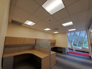 Image of a newly renovated office at the Civic Centre Resource Library in Vaughan, featuring a wooden desk, overhead cabinets, modern lighting, and gray flooring, upgraded by ICON Restoration.