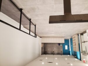 A contemporary kitchen with white cabinetry, gray tiled walls, teal accents, recessed lighting, and pendant fixtures, overhauled by ICON Restoration at Maple Community Centre.