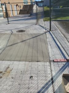 Image of the Chancellor Community Centre restoration by ICON Restoration, featuring freshly poured concrete on the exterior, fenced-off construction area, and a building with stairs under a clear sky in Vaughan.