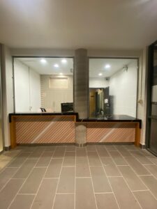 Modern ticket booth at City Playhouse Theatre in Vaughan with a black marble countertop, wooden paneling, and glass enclosure, designed for improved accessibility and efficiency.