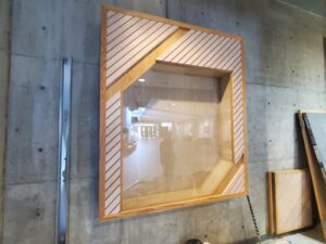 Modern lobby display frame at City Playhouse Theatre in Vaughan with wooden diagonal paneling against a concrete wall, reflecting recent aesthetic upgrades to the cultural venue.