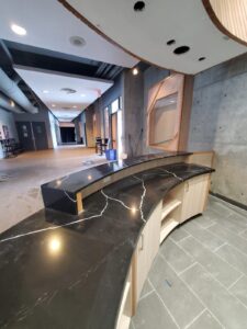 Modern lobby reception desk at City Playhouse Theatre in Vaughan with a black marble countertop, wooden paneling, and recessed lighting, showcasing recent upgrades to the cultural venue.