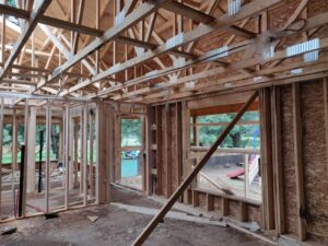 Image of the RAA-1815 Minden Daycare Centre under construction by ICON Restoration, featuring wooden framing, exposed beams, and large windows, with an outdoor play area visible, highlighting structural progress.