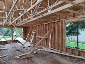 Image of the interior of the RAA-1815 Minden Daycare Centre under renovation by ICON Restoration, featuring wooden framing, exposed beams, and unfinished walls with large windows, showcasing a modern construction site focused on safety and accessibility upgrades.