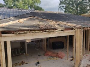 Alt Text: A construction site at RAA-1815 Minden Daycare Centre showing a partially repaired roof with exposed framing, new wooden supports, and construction materials, restored by ICON Restoration.